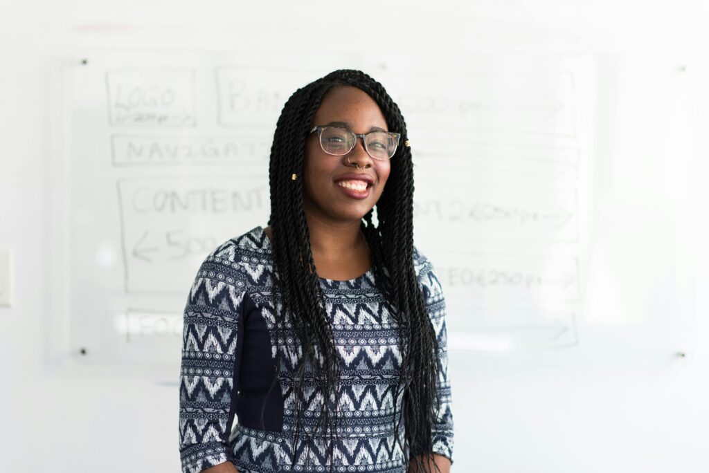 Confident young woman smiling in front of a whiteboard in an office. Ideal for business and lifestyle content.